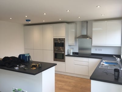 Modern white kitchen with black countertops, island, stainless steel appliances, and recessed lighting